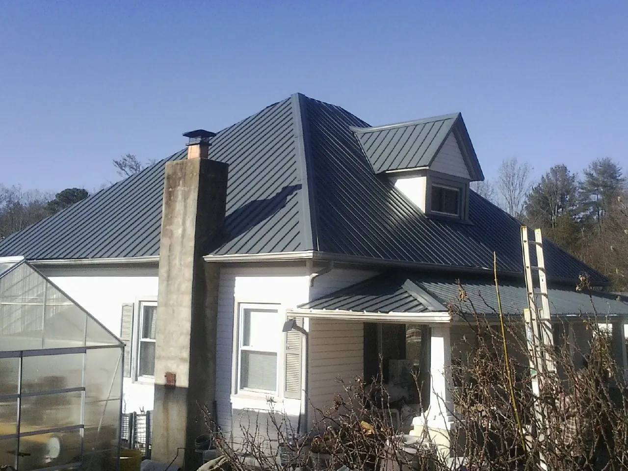 Dark blue standing seam metal roof on a white farmhouse with dormer — Slate & Tile Roof Repair by Roofing Brothers in Lomax