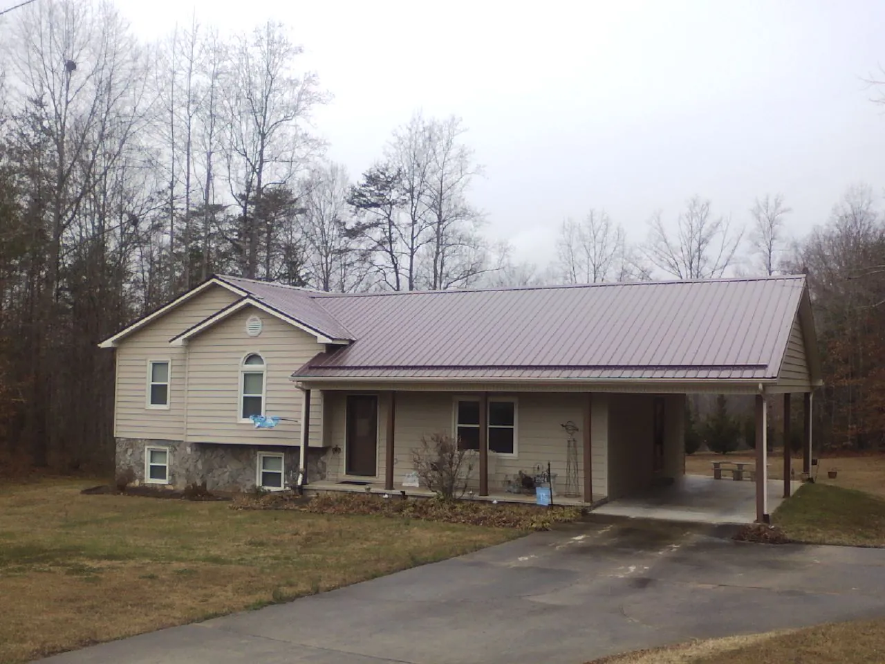 Burgundy metal roof on a tan split level home with an attached carport in Lomax