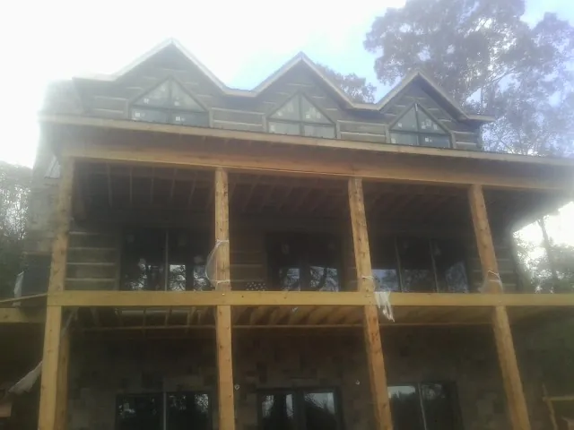Dormers and porch framing on a large log home under construction — Roof Coating work by our crew in Lomax