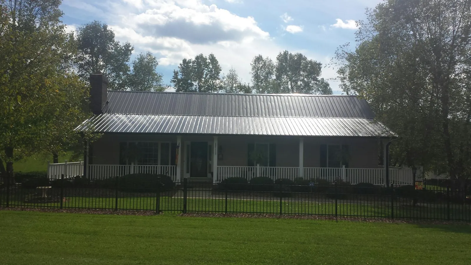 Gray metal roof on a brick ranch with a full width front porch — Gutter Guard Installation work by our crew in Lomax